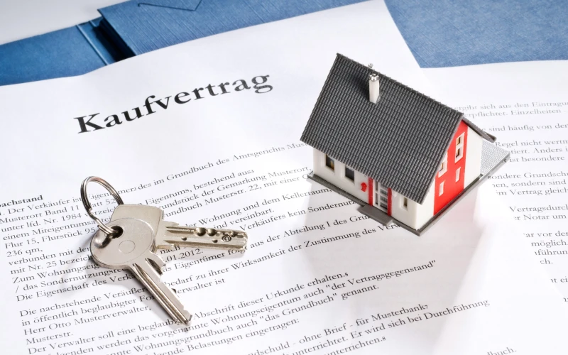 Kaufvertrag mit Hausschl&uuml;ssel und kleinem Hausmodell